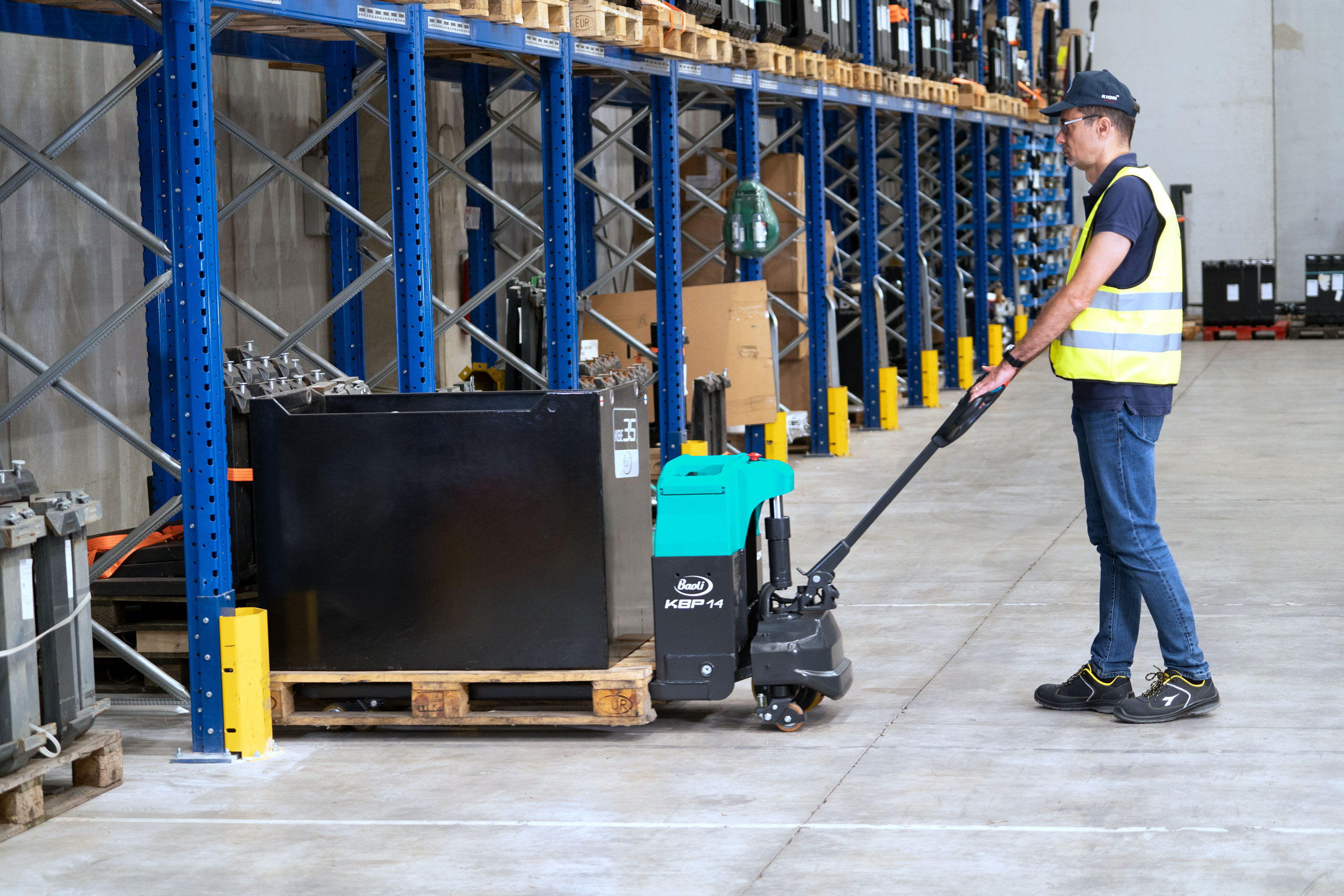 Baoli KBP 20 Niederhubwagen im Lagereinsatz beim Ziehen einer beladenen Palette